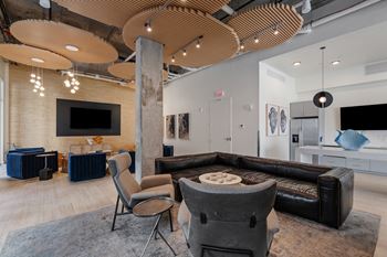 A modern living room with a black leather couch and a wooden ceiling.